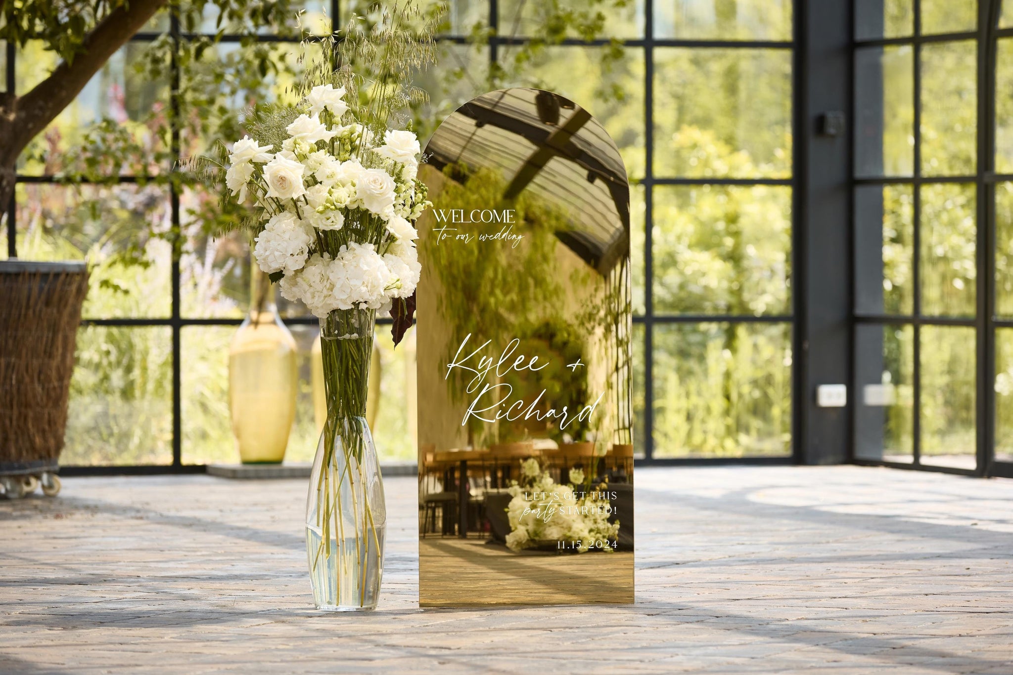 Gold mirror arched welcome sign displayed at wedding ceremony entrance

