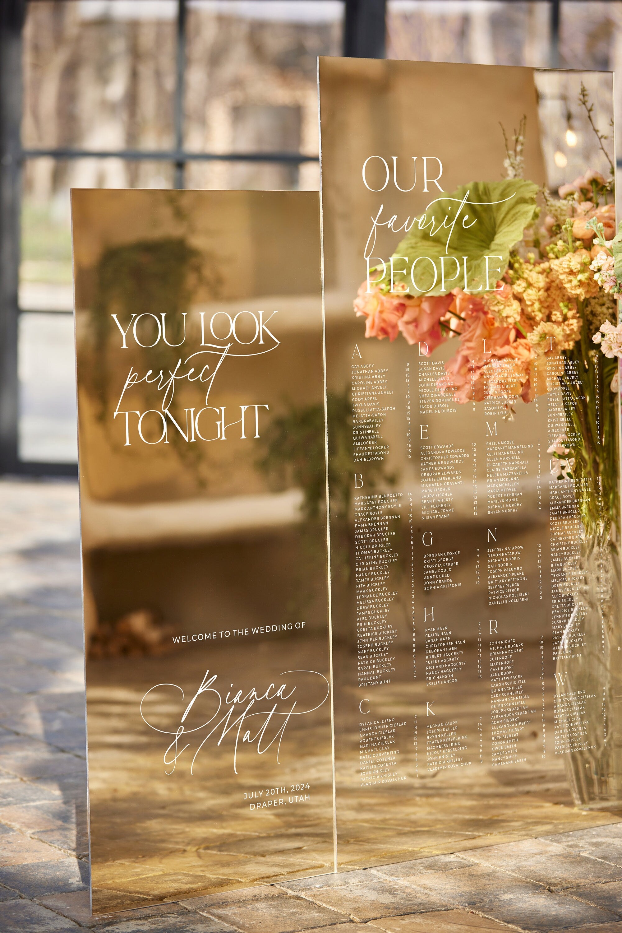 Wedding seating chart and welcome sign in gold mirror acrylic displayed at elegant reception
