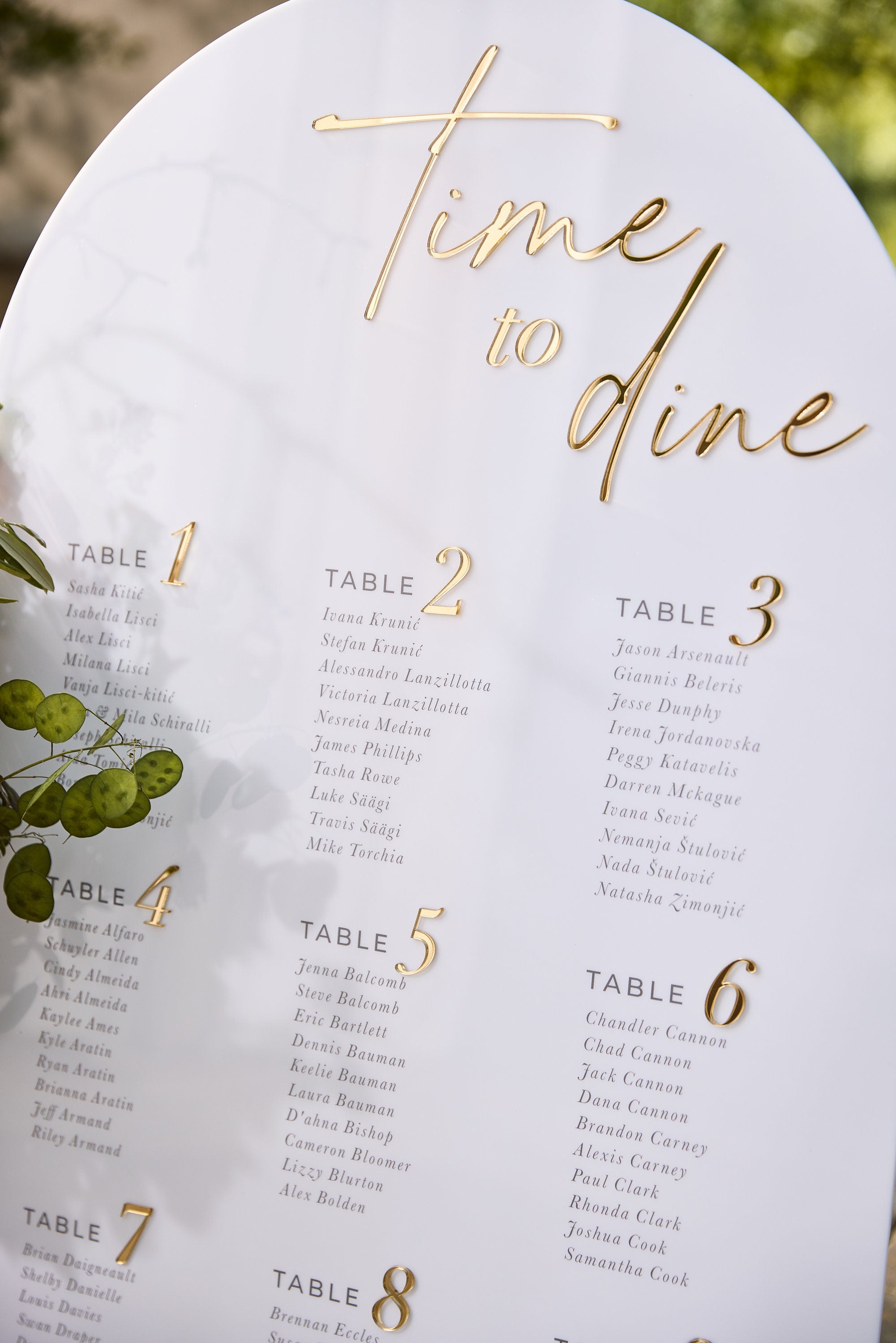 Close-up of 3D gold mirror lettering on white acrylic arched seating chart 
