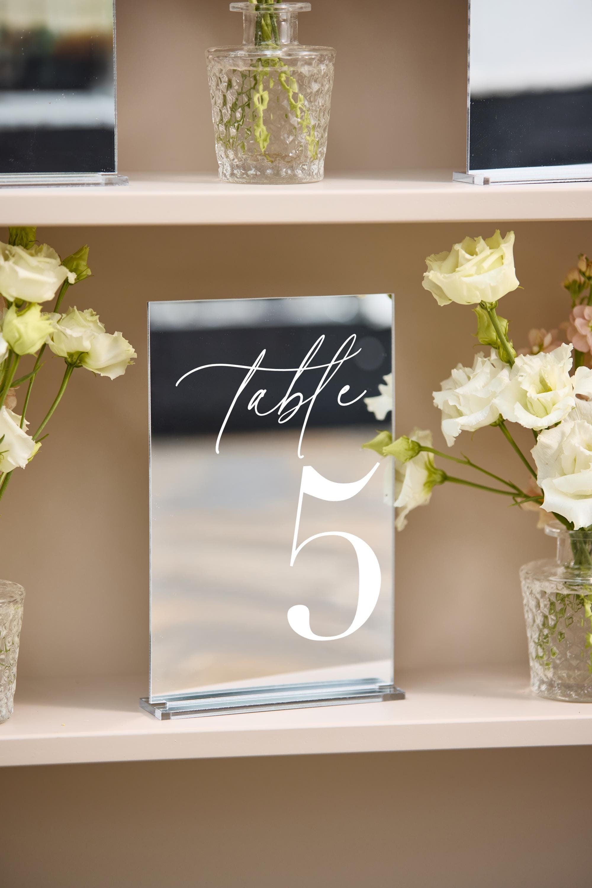 Close-up of silver mirror wedding table number with reflective finish and stand
