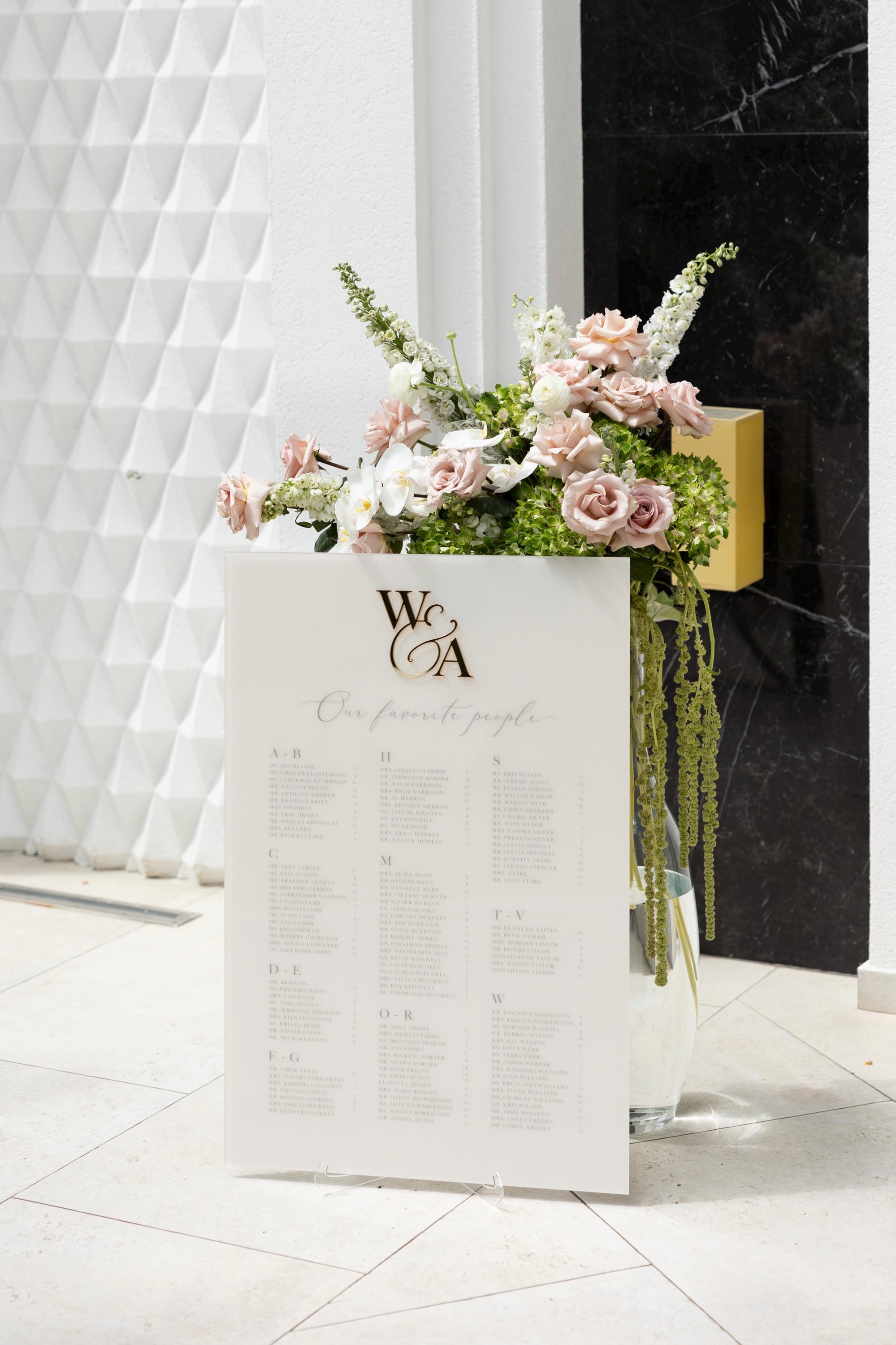 Beige and gold wedding seating chart with UV-printed alphabetical guest names and table numbers
