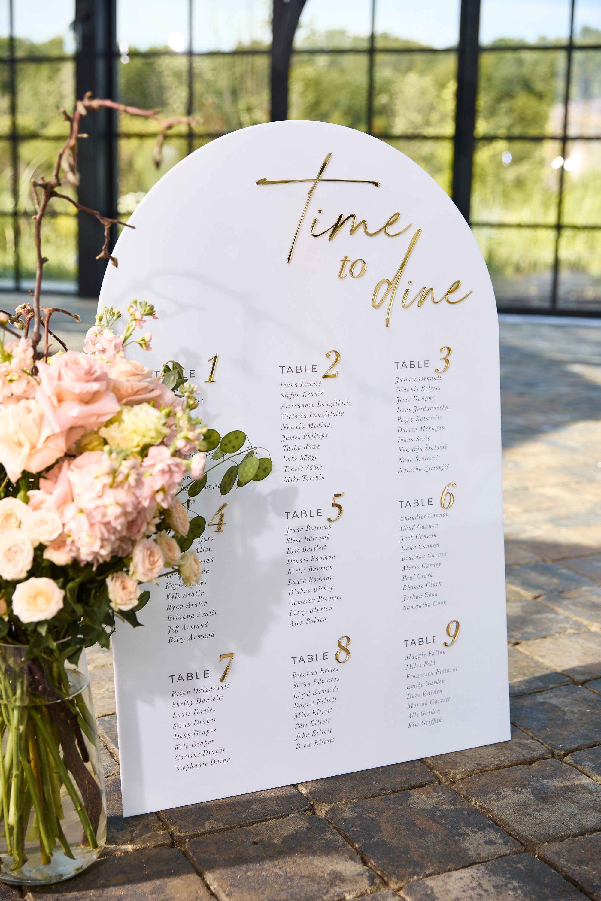 Wedding seating chart white acrylic with 3D gold mirror text at modern reception 
