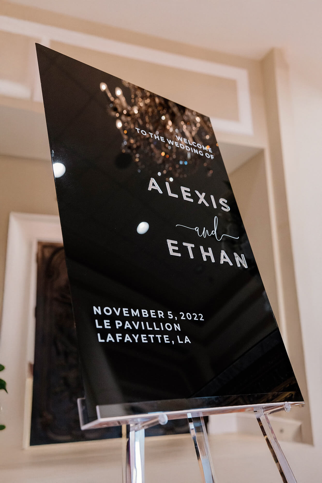 Close up detail of 3D silver mirror lettering mounted on matte black acrylic showing raised texture.