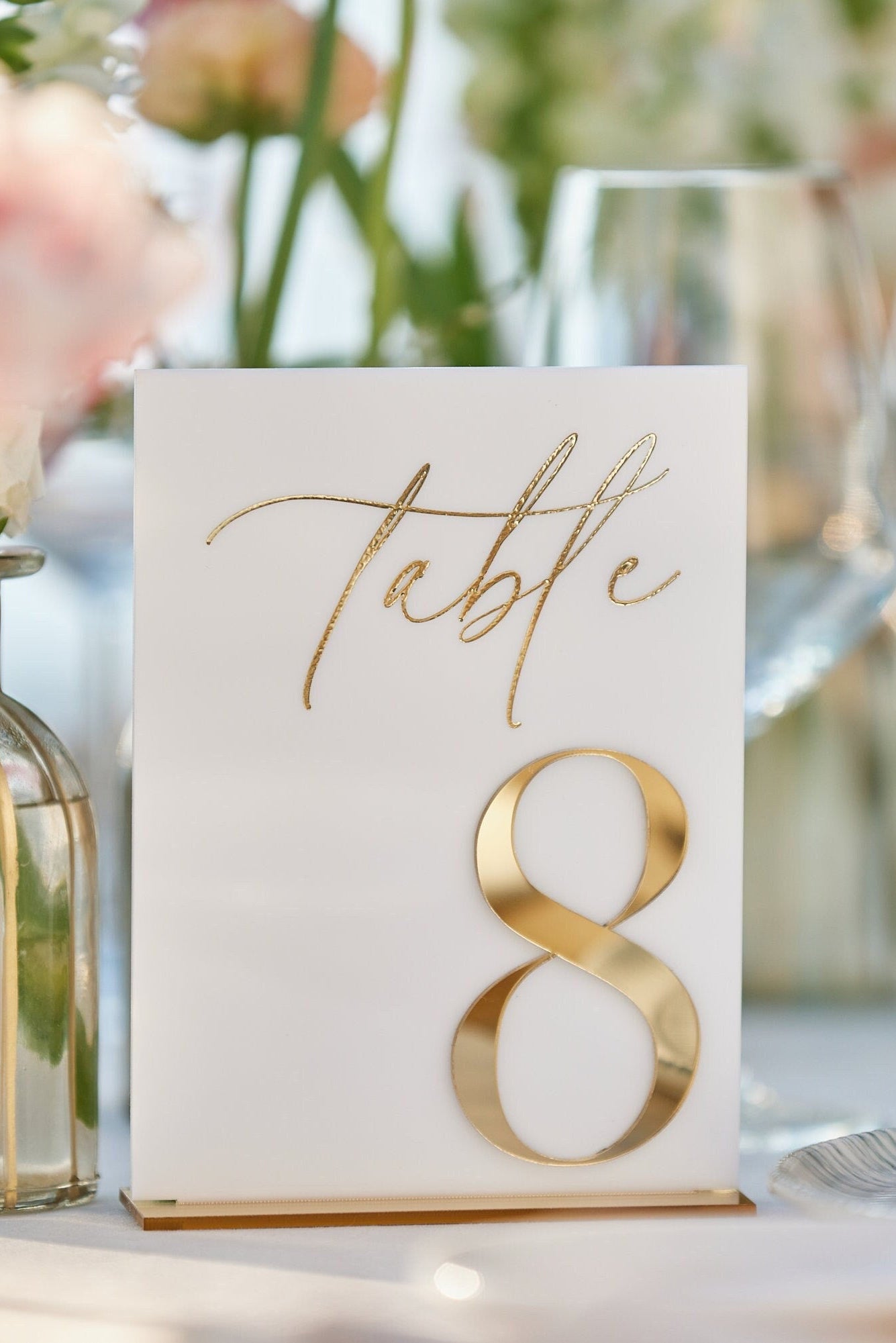Close-up of white acrylic wedding table number with 3D gold mirror number and stand
