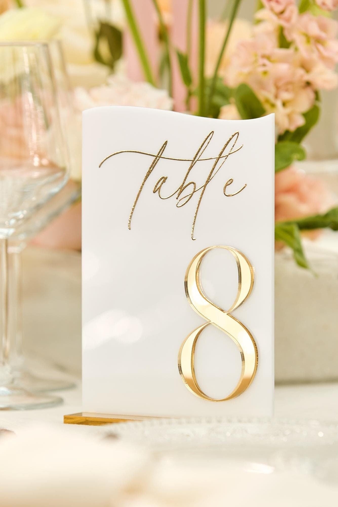 Close-up of white acrylic table number with 3D gold mirror and gold stand
