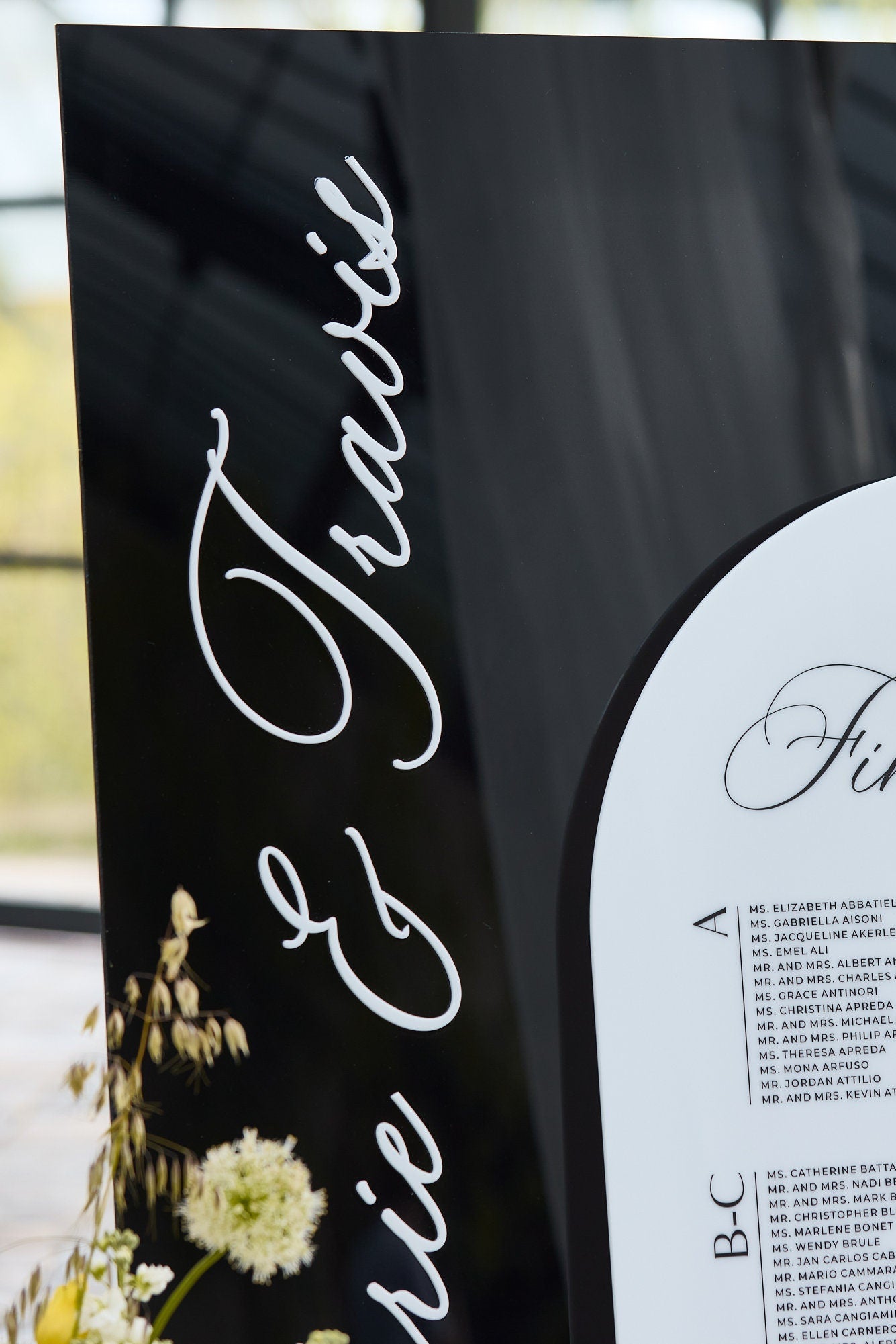 Close-up of black acrylic header and UV-printed guest names on white seating chart
