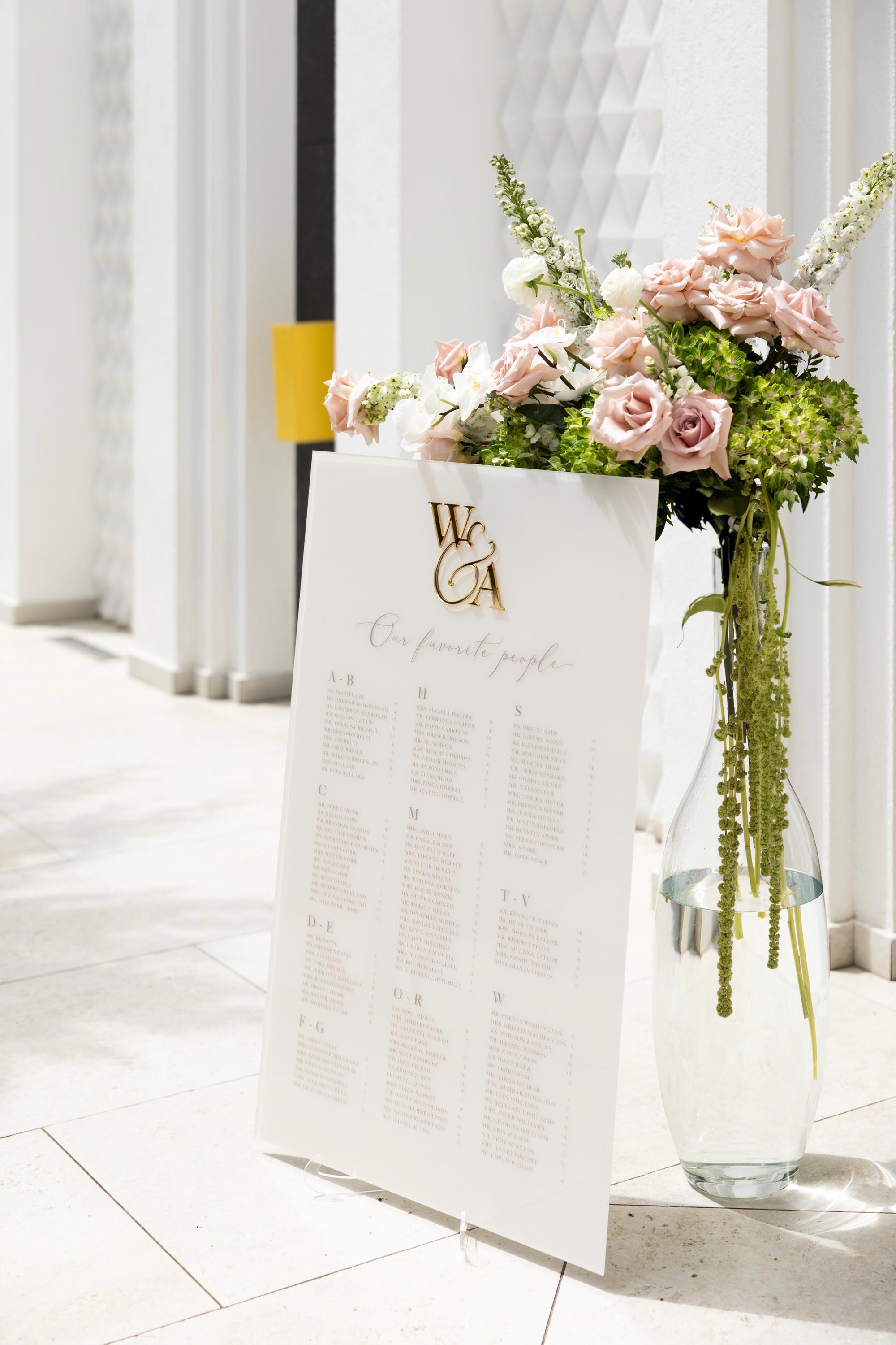 Beige acrylic wedding seating chart with 3D gold mirror monogram and guest list
