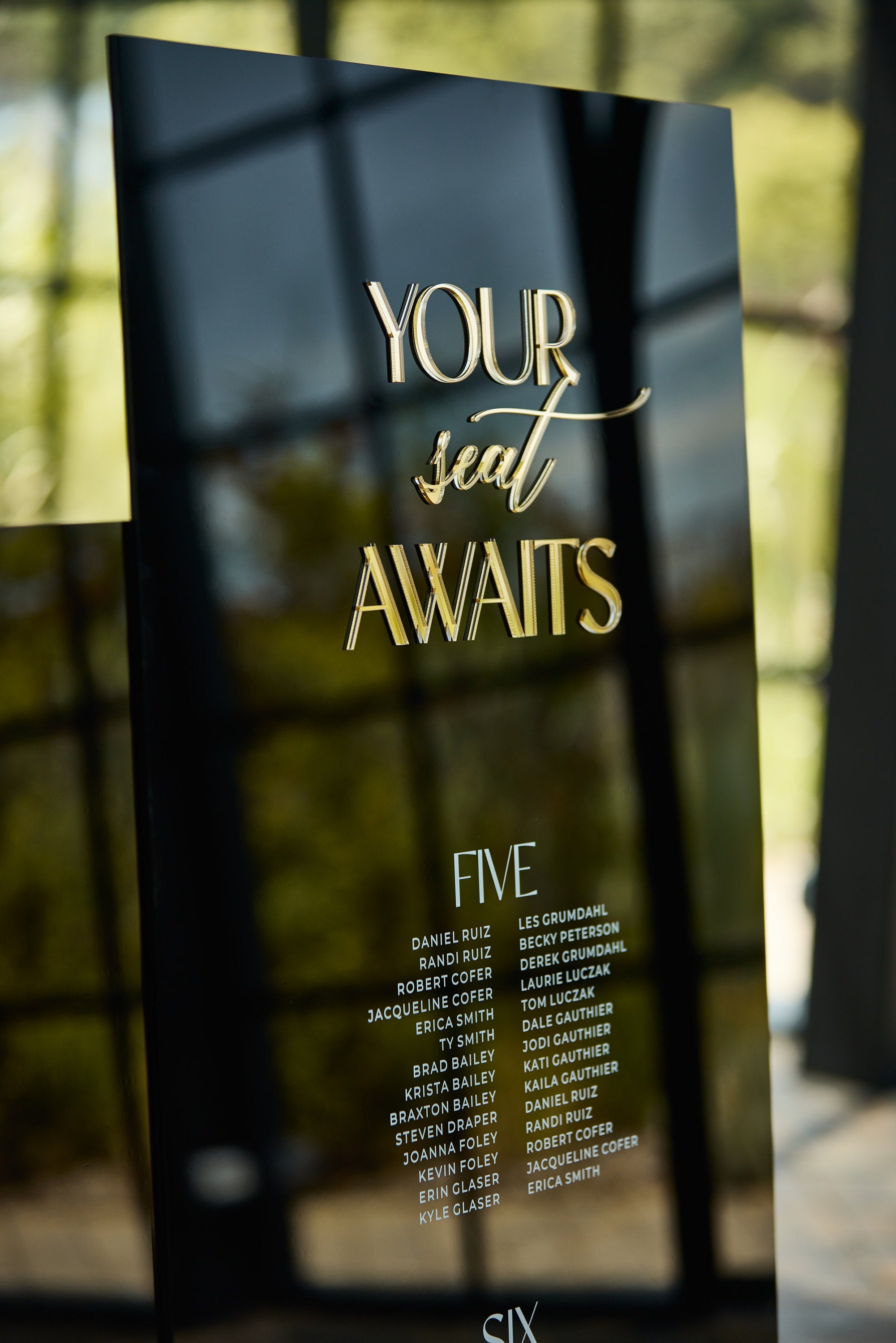 Wedding welcome sign in black acrylic with Your Seat Awaits message

