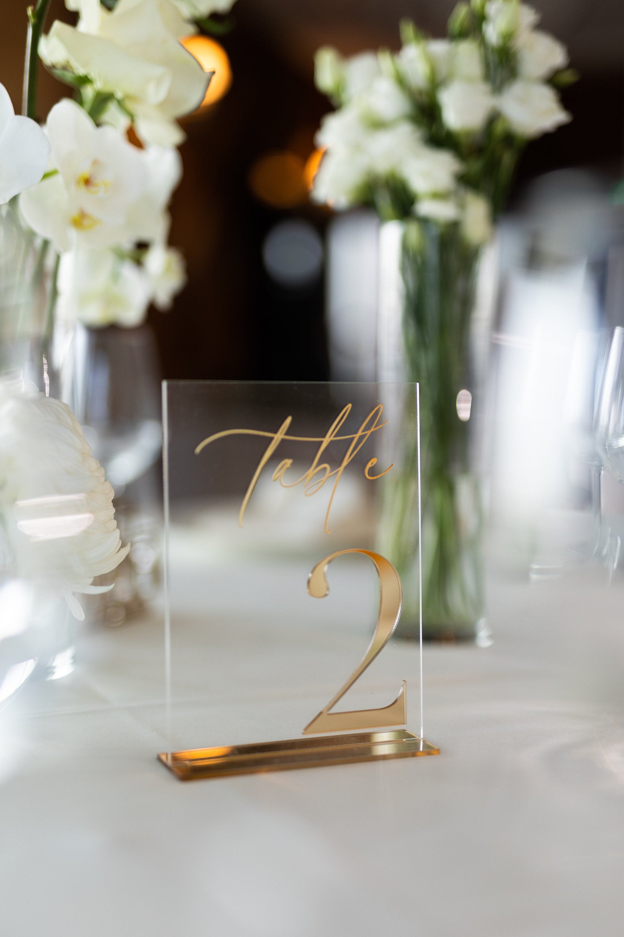 Transparent acrylic table sign with 3D gold mirror number on display
