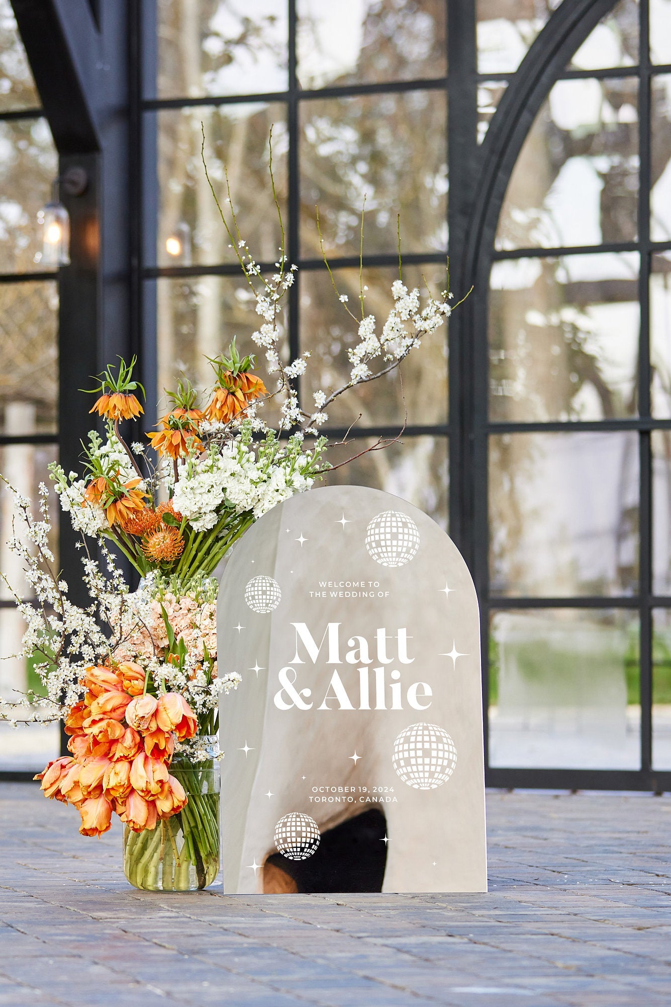 Silver mirror arched welcome sign with disco ball for retro wedding reception
