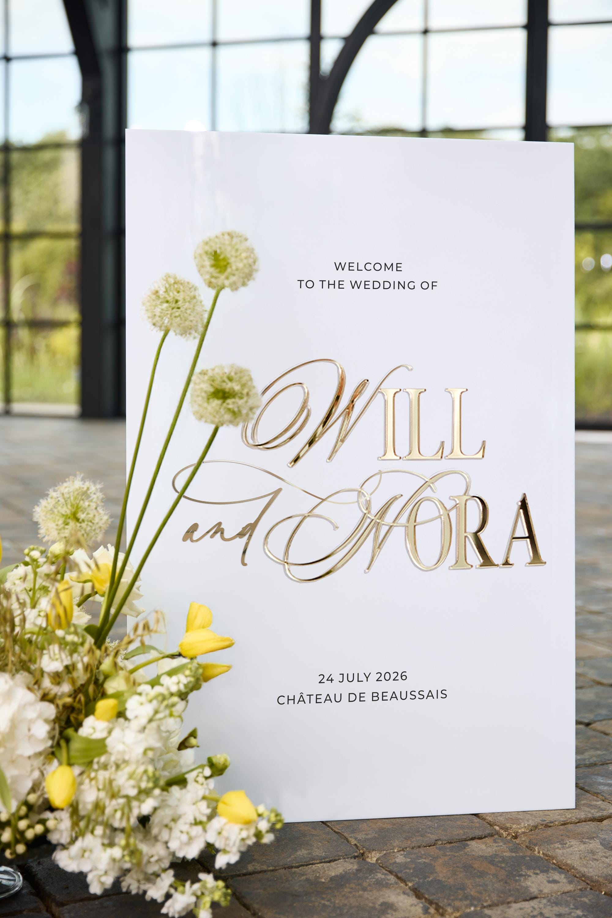 Close-up of white acrylic welcome sign with 3D gold mirror personalized names
