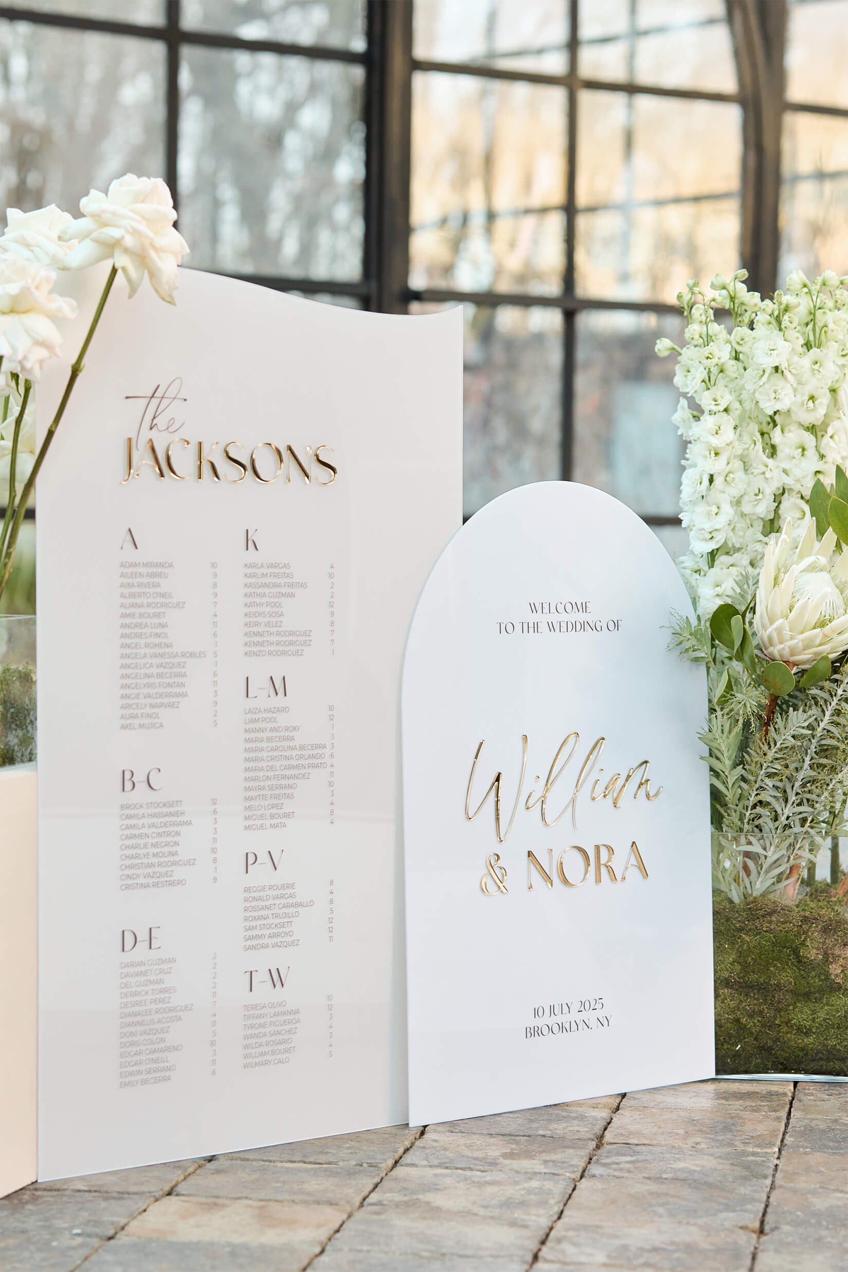 Coordinated wedding signage set featuring a beige acrylic seating chart and a white acrylic welcome sign with matching 3D gold mirror names.