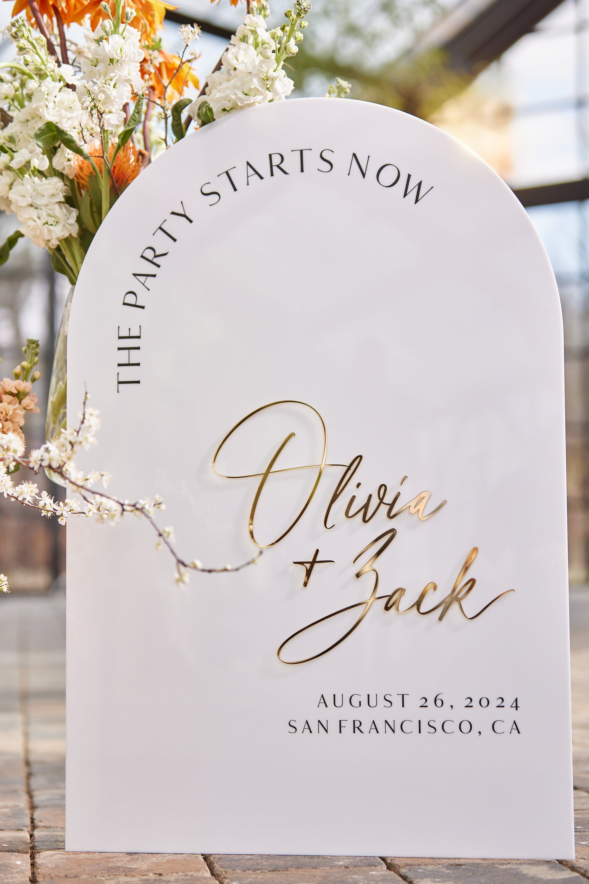 White acrylic arched welcome sign displayed at garden wedding ceremony entrance
