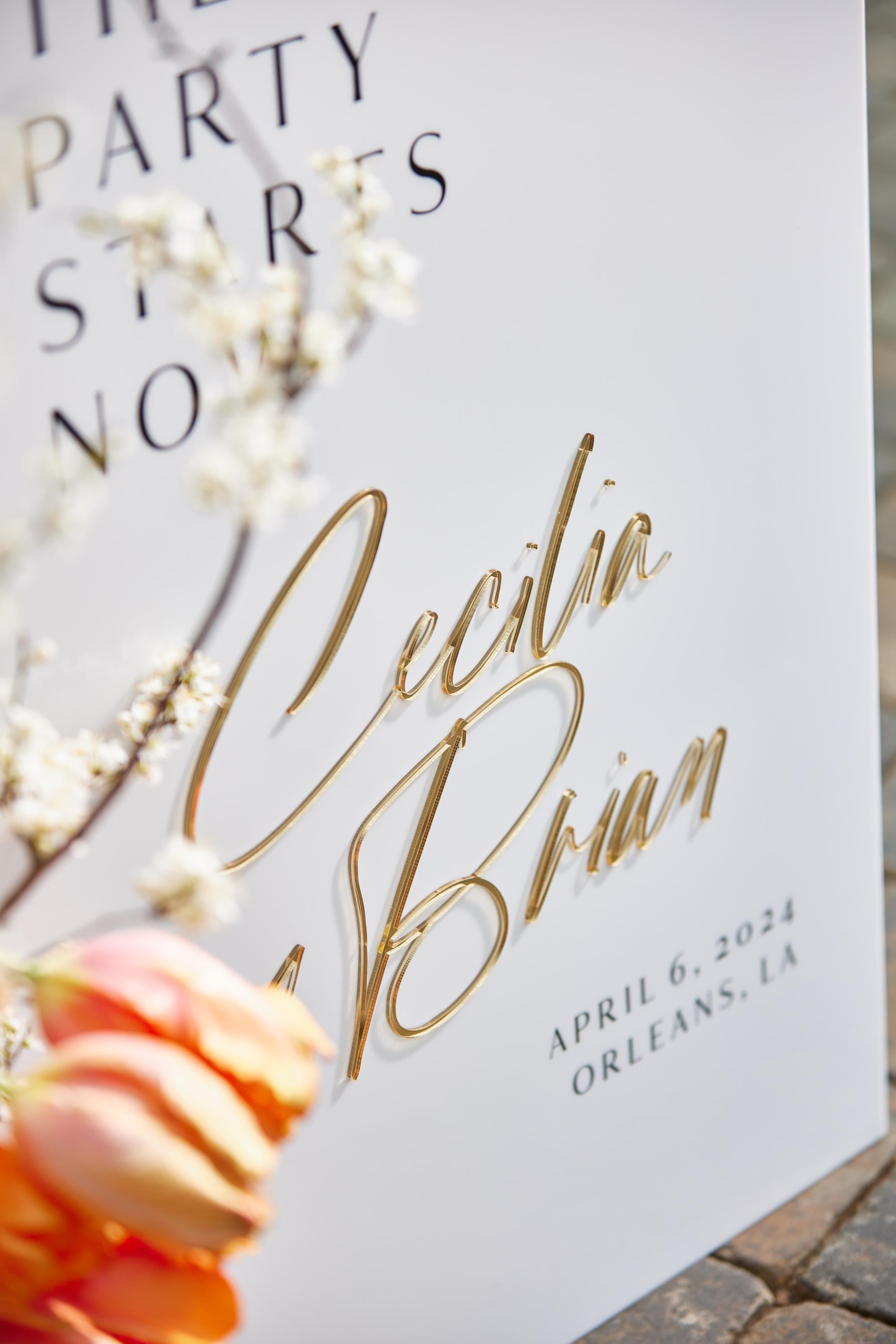 Close-up of white acrylic wedding sign with 3D gold mirror lettering detail
