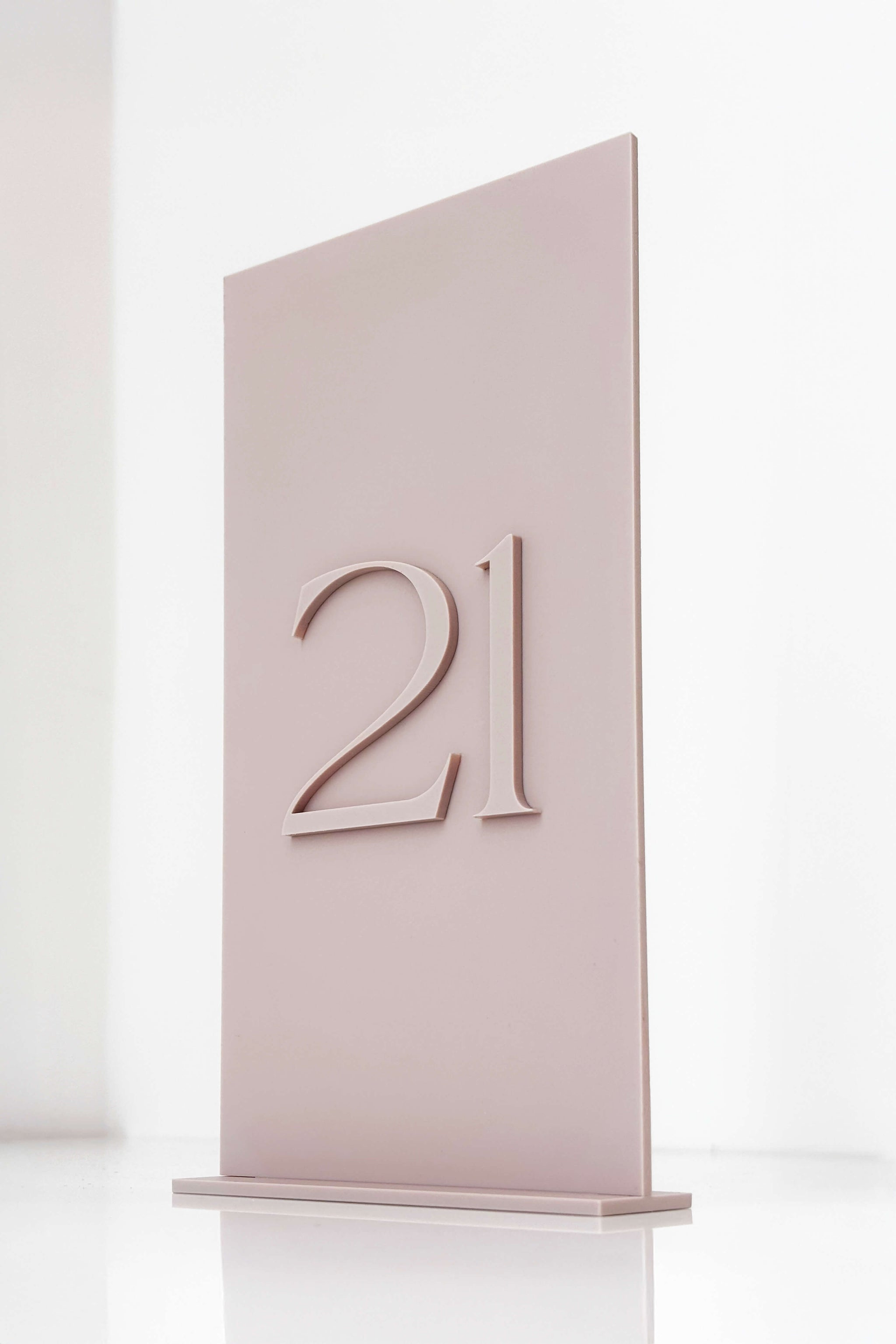 Close up detail of raised 3D numerals on a dusty pink acrylic background showing texture.