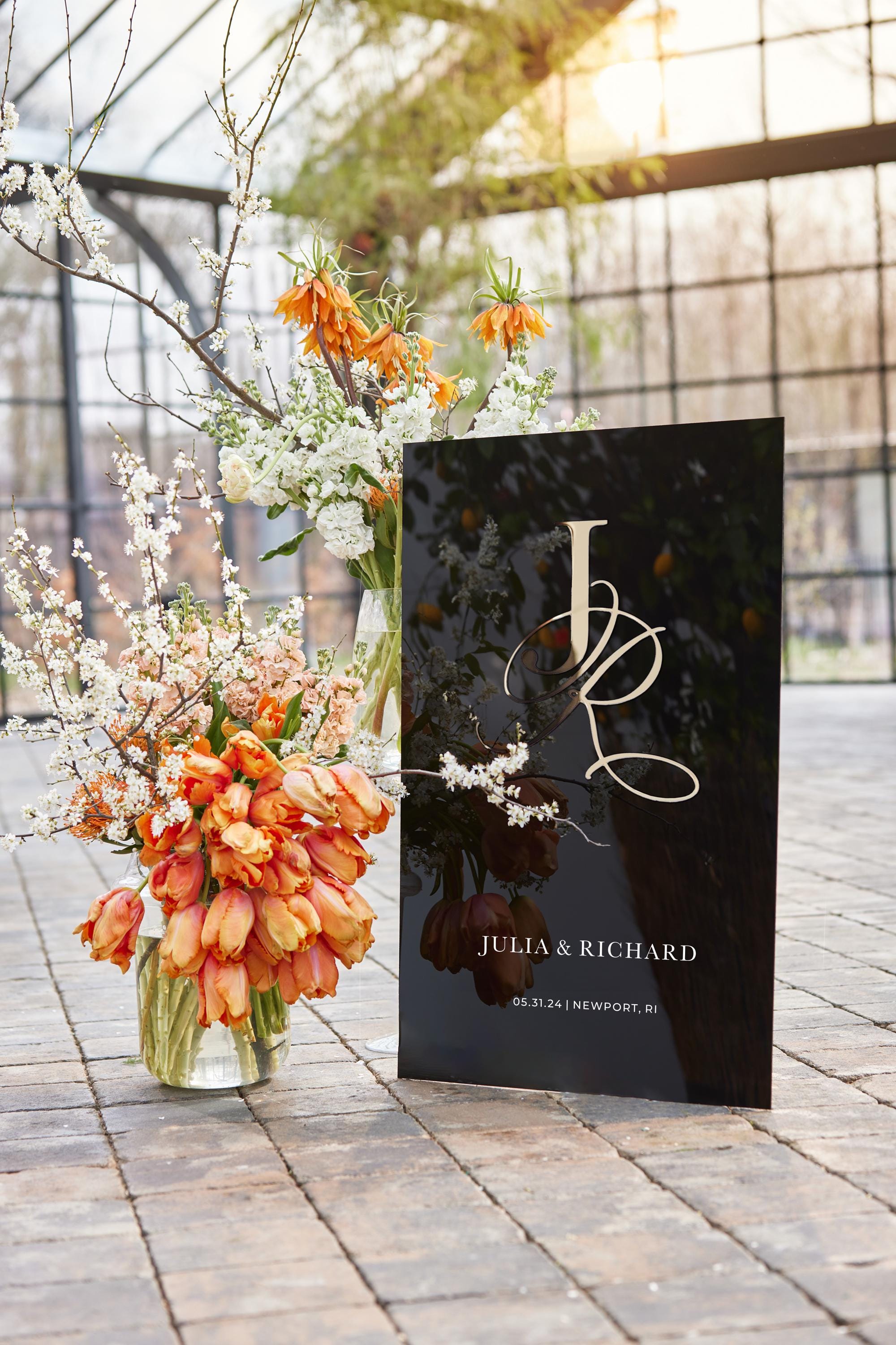 Modern wedding welcome sign with gold monogram at outdoor venue