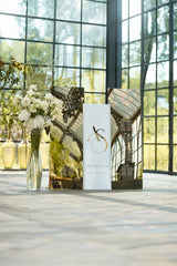 Matching set of white and gold mirror wedding signage, featuring a 3D welcome sign with initials and large seating charts organized by table number.