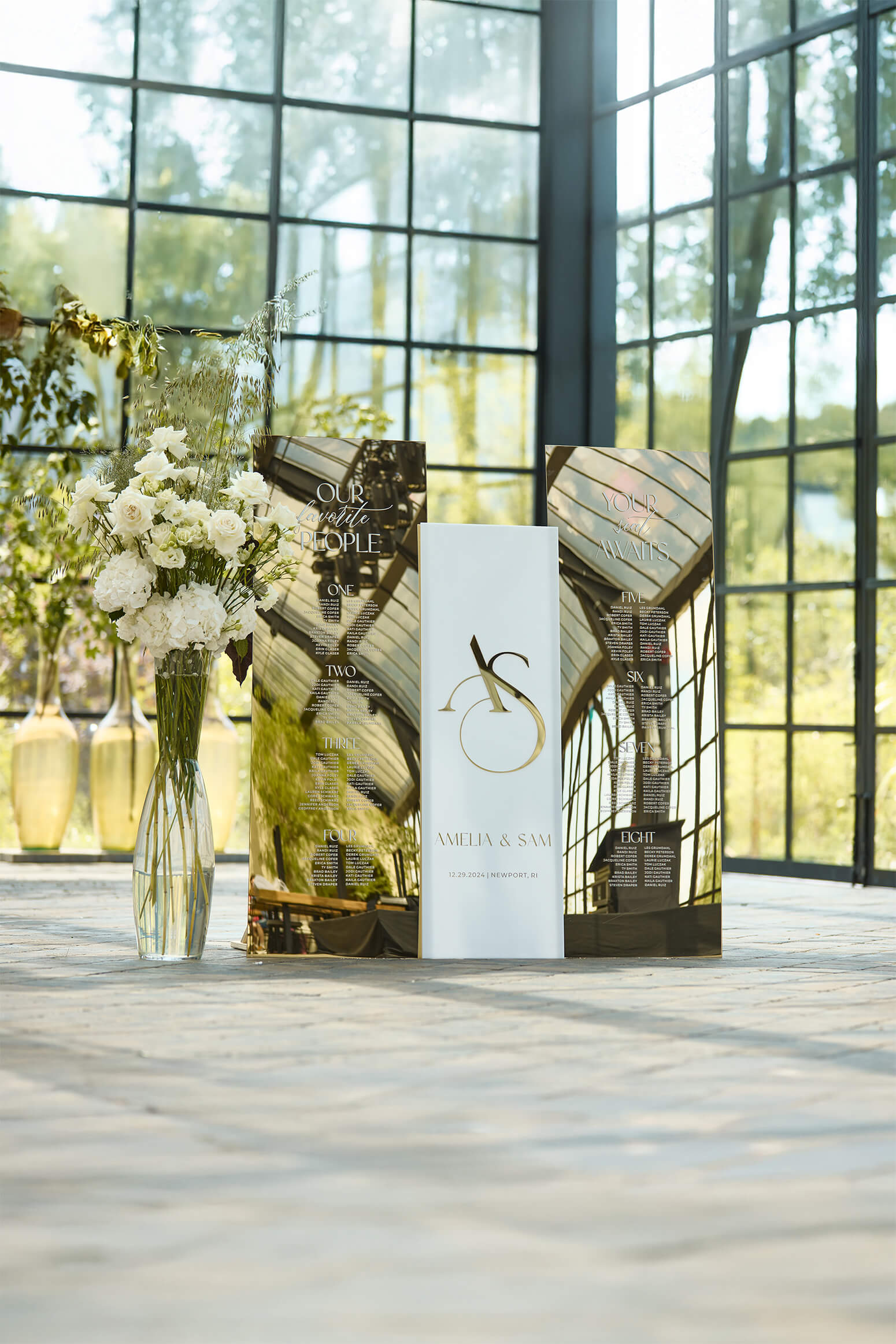 Matching set of white and gold mirror wedding signage, featuring a 3D welcome sign with initials and large seating charts organized by table number.