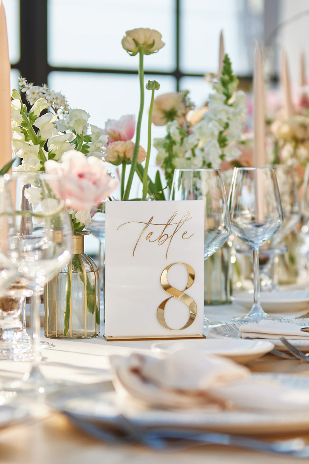 White acrylic wedding table numbers on gold mirror stands.