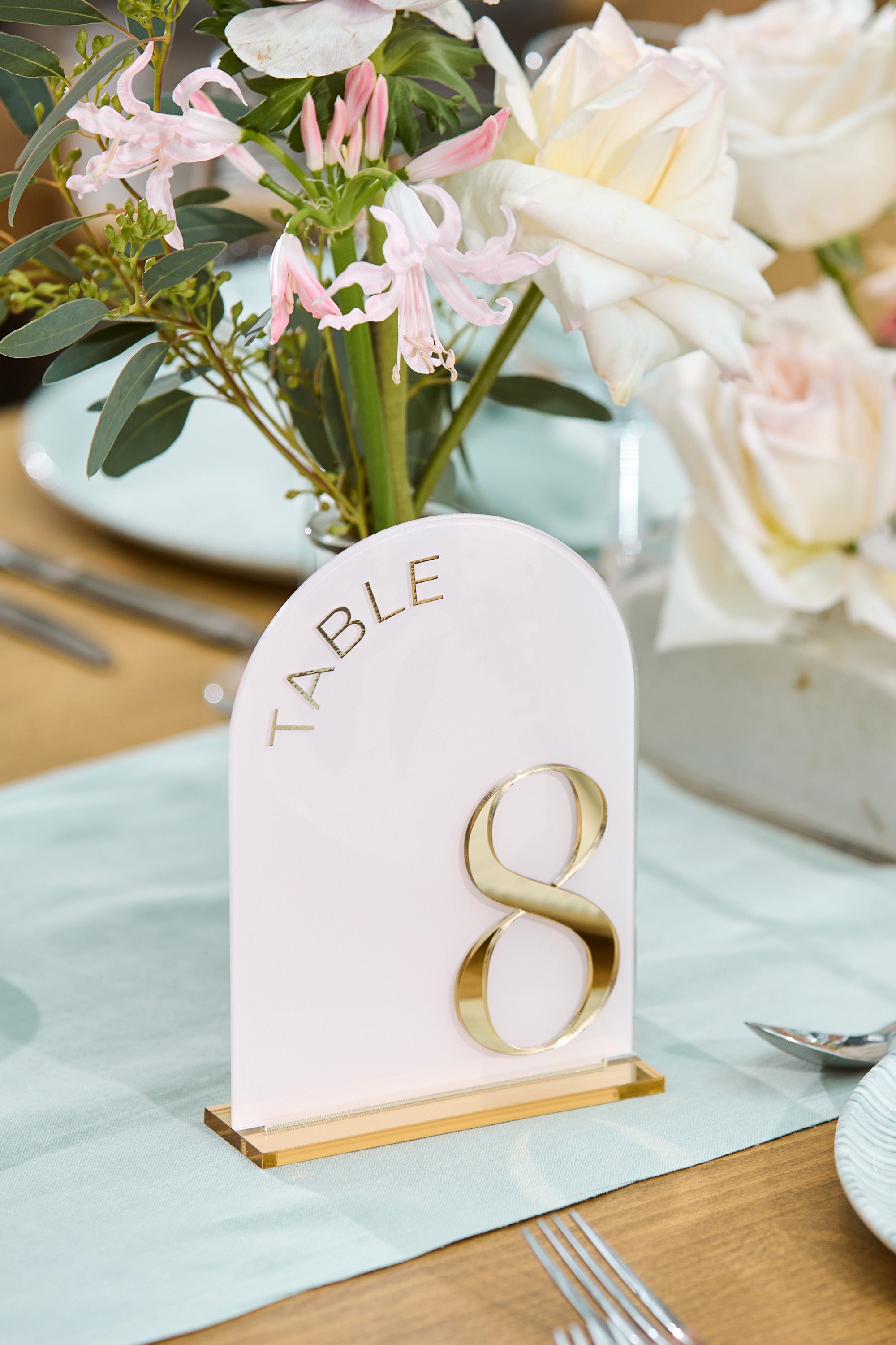 Modern arched pink table number with gold lettering.