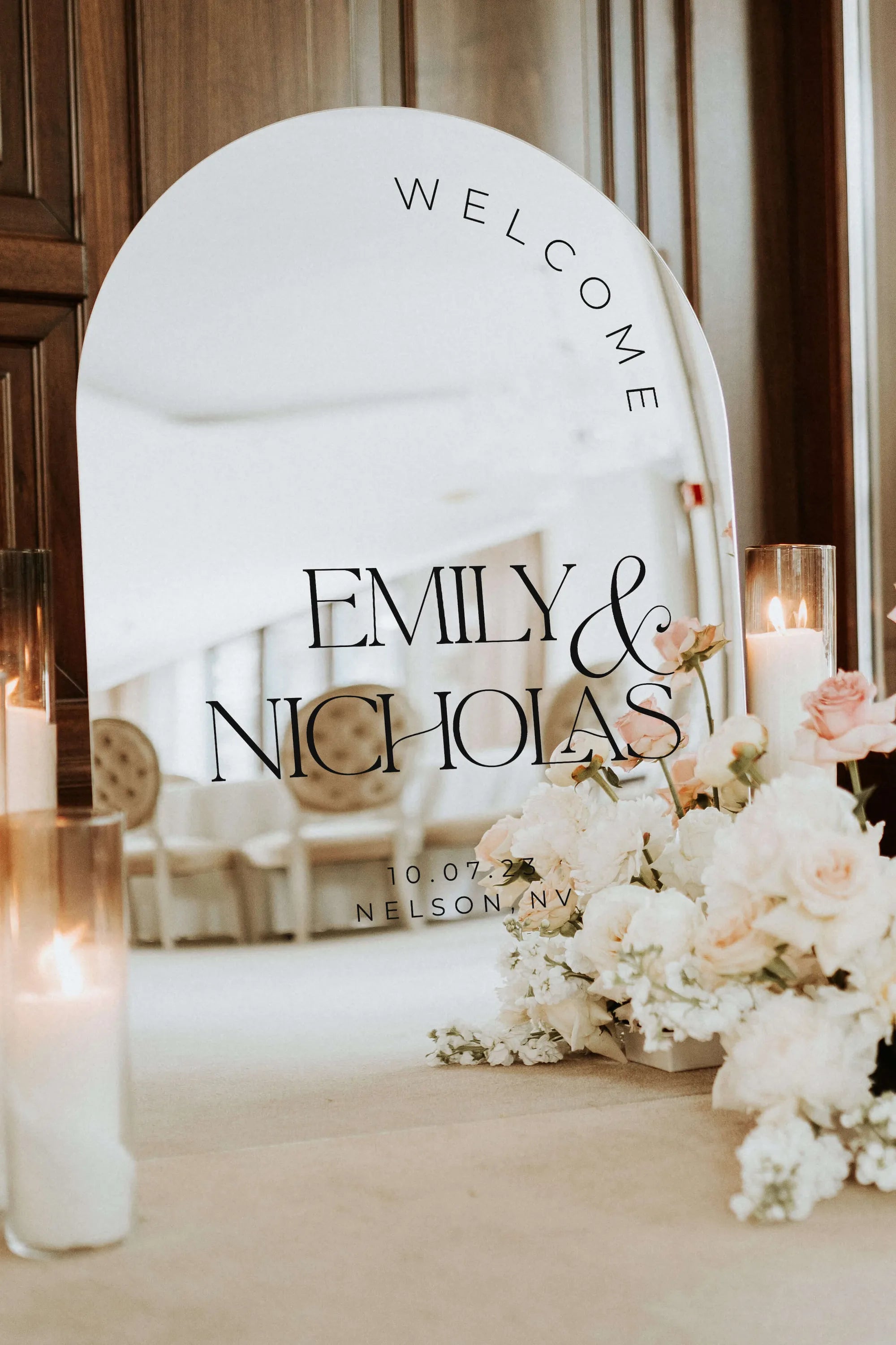Arched silver mirror acrylic wedding welcome sign with personalized names displayed at ceremony entrance
