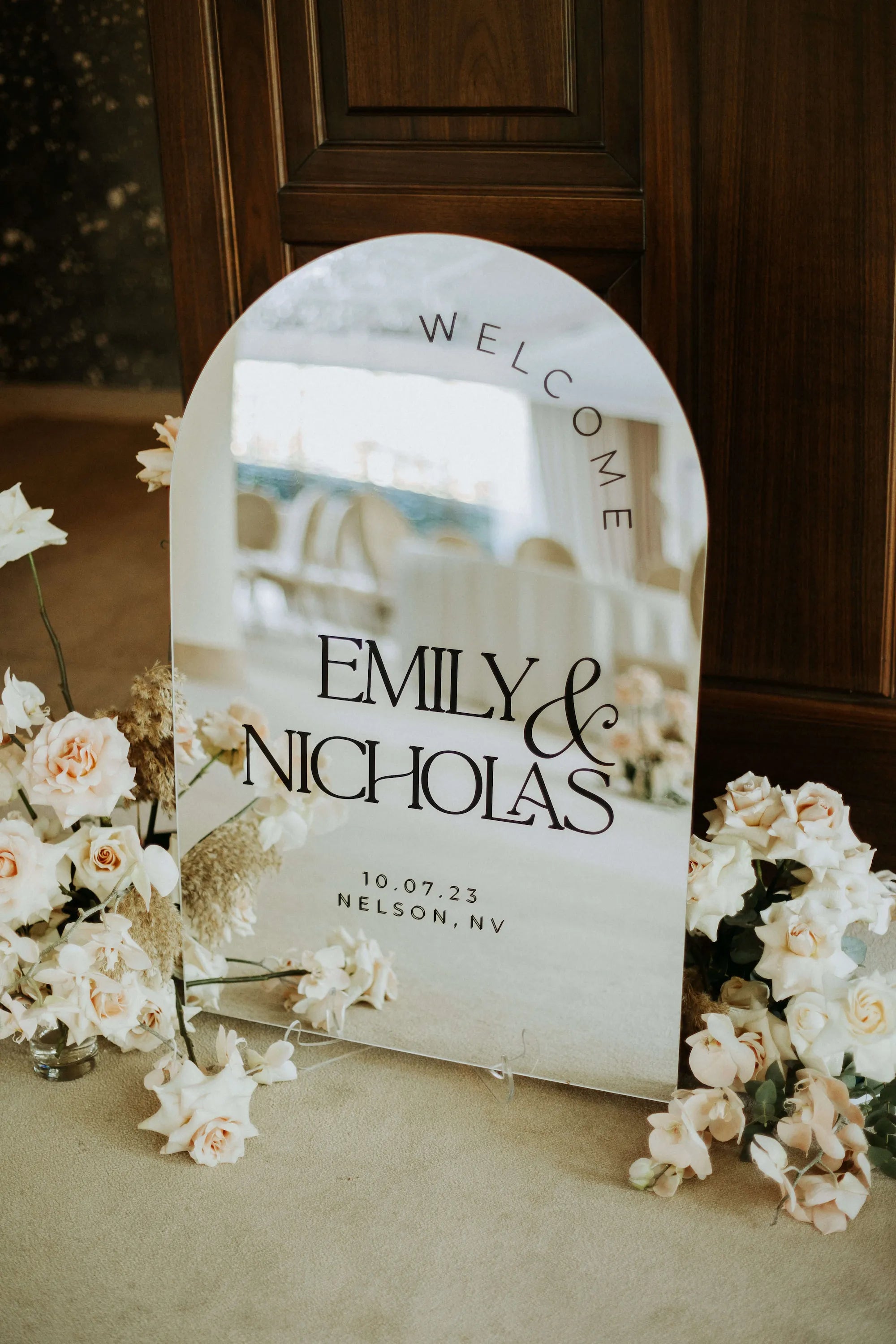 Arched silver mirror wedding welcome sign highlighting mirror acrylic finish and custom names and date